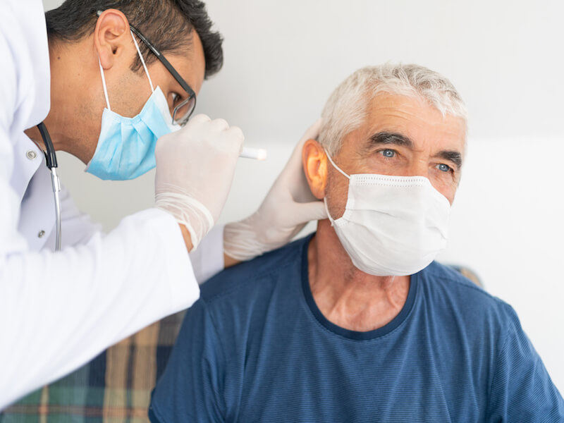 Mature man getting his hearing checked during the pandemic.