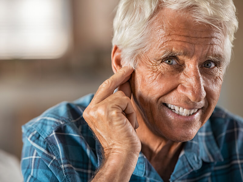 Elderly man can’t hear because his hearing aid needs a new battery.