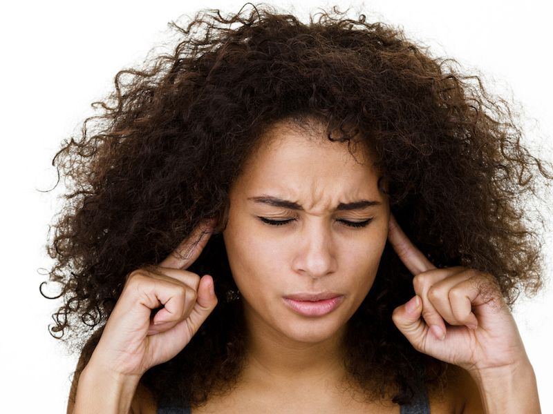 Woman with sudden sensorineural hearing loss holding ears.