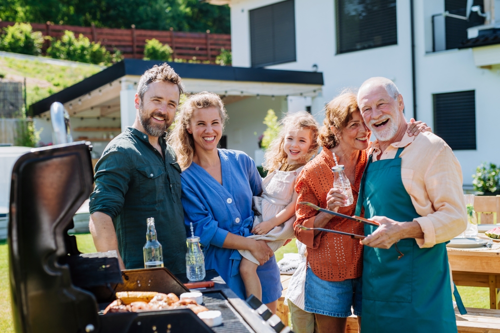 Multi generation family grilling outside at backyard party.