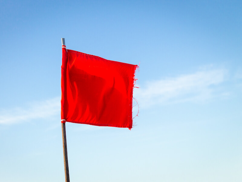 Red flag on a wooden pole against a blue sky symbolizing hearing loss symptoms 
