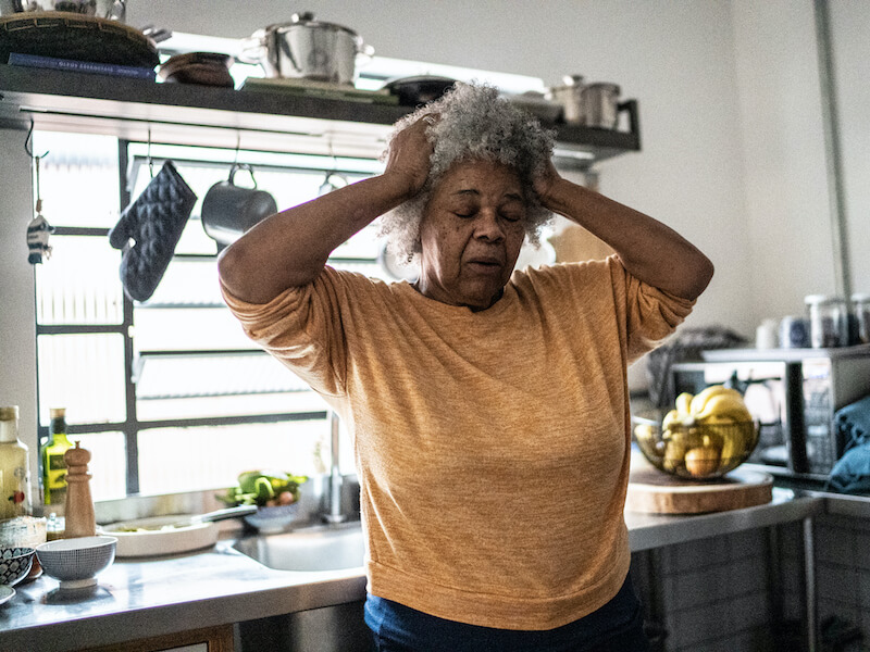 Confused woman suffering from hearing loss experiencing forgetfulness  in her kitchen