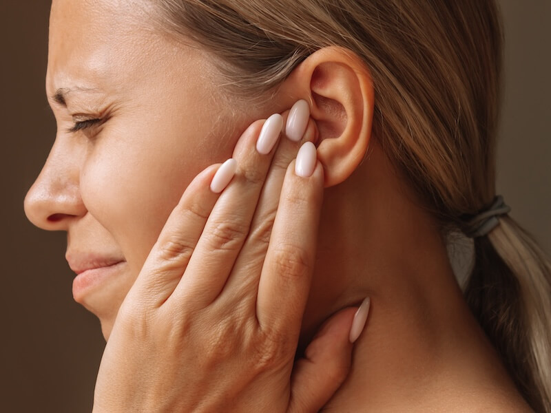 Young blonde woman holding her ears with her hands. Pain and tinnitus