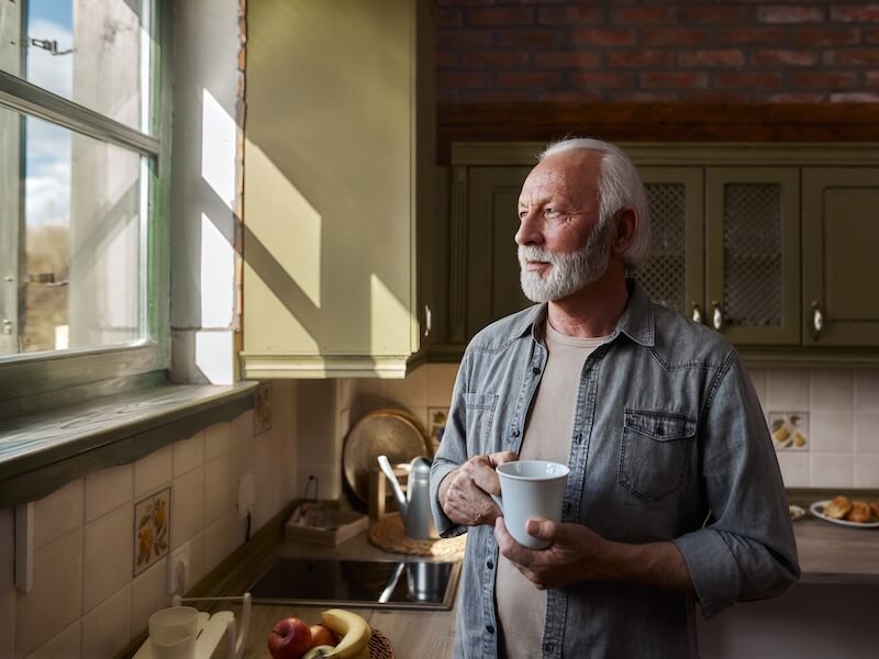 Older man staring out of the window wondering is his hearing will come back